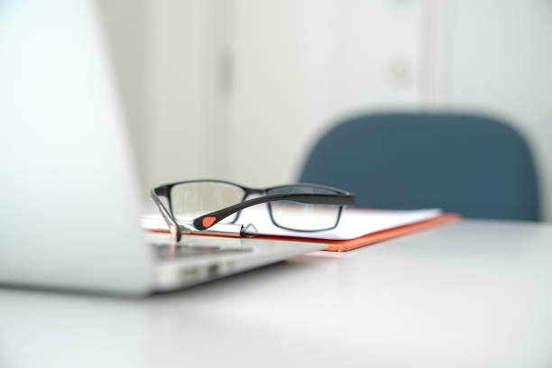 istock Office table view with chair, laptop, papers and focus on reading glasses 1183689392
