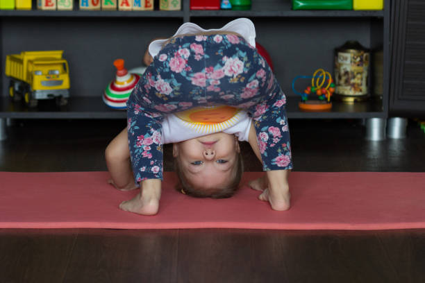 istock Little girl bending down making physical training indoor 1183697089
