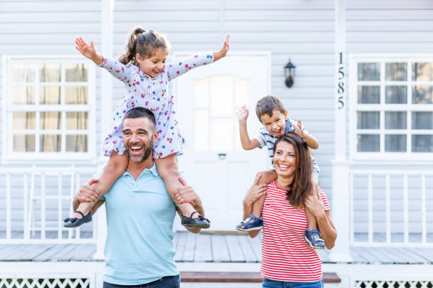 istock Parents having fun in front yard carrying children piggyback 1183697752