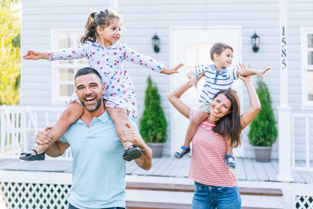 istock Parents having fun in front yard carrying children piggyback 1183697754