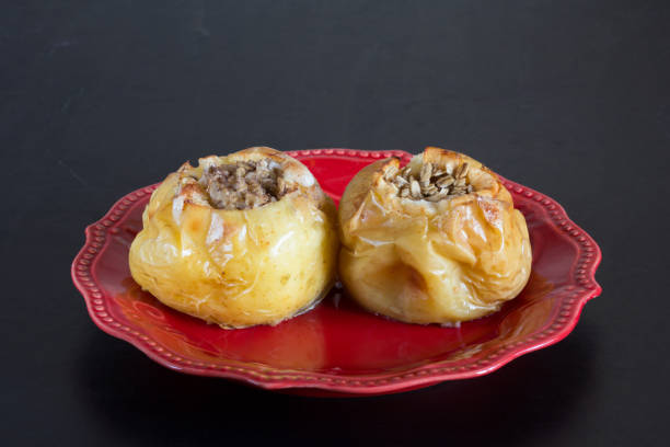 istock Two baked apples filled oats on red plate on black background 1183698197