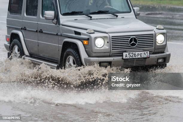 Automobile Mercedesbenz Gwagen Driving On Flooded Street Road Over Deep Muddy Puddle Splashing Drop Of Spray Water From Wheels Stock Photo - Download Image Now
