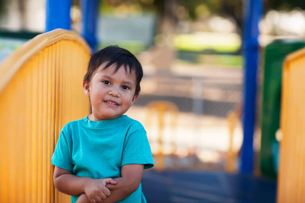 A cute little boy holding on to his arm after an injury at a kids playground. stock photo