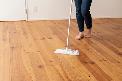 Feet of young woman mopping the floor of wood