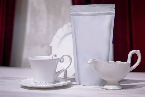 Template of paper ecological bag for storing coffee, tea on the background of cups and utensils. Vacuum packaging for christmas and new year present