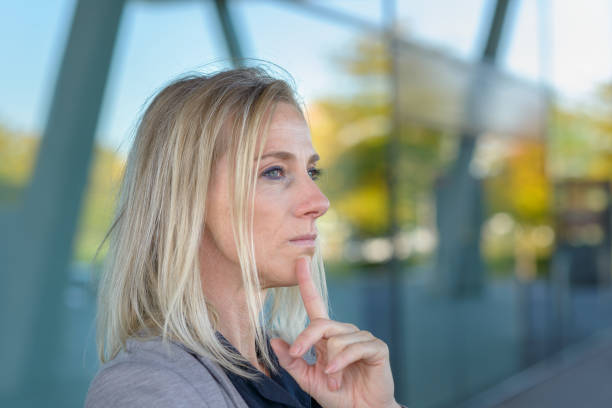 Attractive woman taking a moment to relax and meditate with her finger to her chin outdoors in a concept of quality time