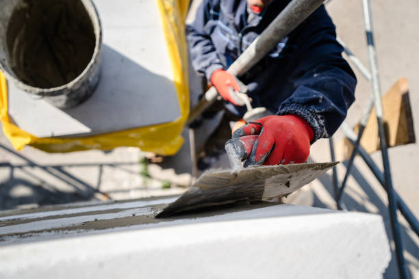 istock Construction worker plastering a wall with trowel cement mortar applying adhesive cement on the Autoclaved aerated concrete AAC brick high angle close up on hand holding the tool outdoor 1183707644