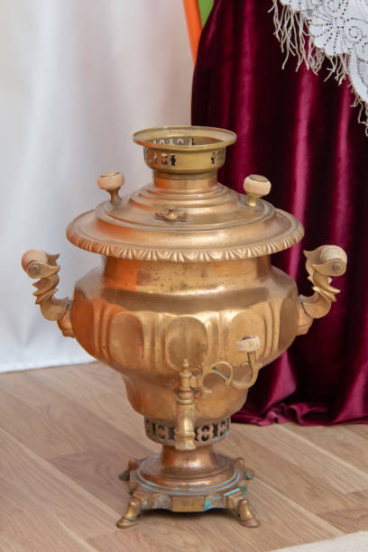 gold color metal samovar on a background . samovars are typically crafted out of plain iron, copper, polished brass, bronze, silver, gold, tin, or nickel . - old fashioned domestic kitchen old close up imagens e fotografias de stock