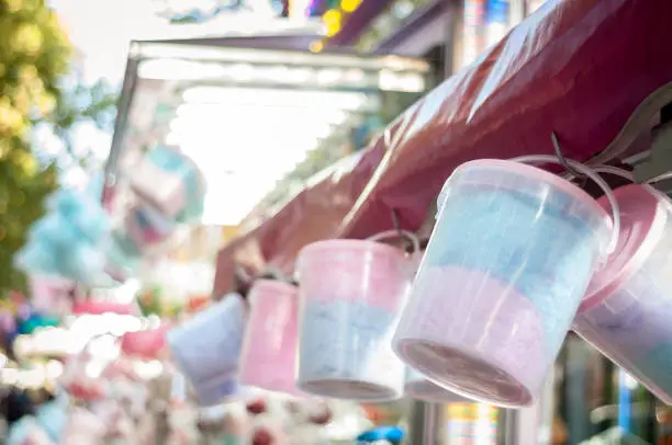 Cotton candy containers hanging from a funfair stand with blurred background