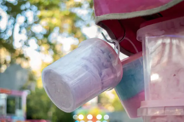 Cotton candy containers hanging from a funfair stand with blurred background