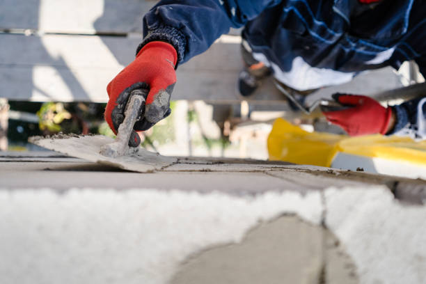 オートクレーブの気口コンクリートaacレンガの高角を手元に閉じた粘着性セメントセメントを塗布したコテセメントモルタルで壁を漆喰する建設労働者は、ツールを屋外に保持します - trowel plaster construction worker work tool ストックフォトと画像