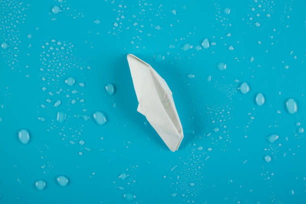 paper boat is sinking into the sea. - brunt imagens e fotografias de stock