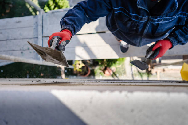 istock Construction worker plastering a wall with trowel cement mortar applying adhesive cement on the Autoclaved aerated concrete AAC brick high angle close up on hand holding the tool outdoor 1183709446