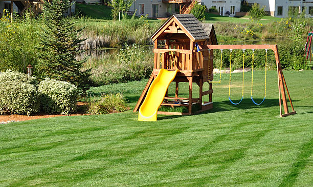 Back yard wooden play set surrounded by greenery Back Yard Wooden Swing Set on Green Lawn jungle gym stock pictures, royalty-free photos & images