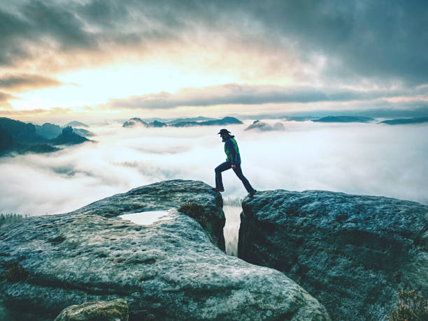 caminhada nas montanhas do outono. o homem permanece acima da névoa pesada no vale - exploration mountain ice jumping - fotografias e filmes do acervo