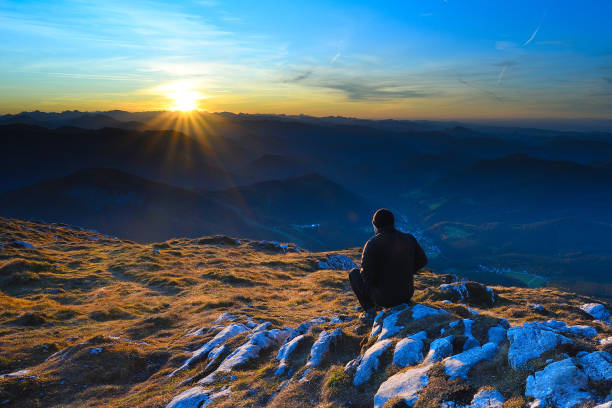 istock Man sit on cracked summit in Alps watching amazing sunset 1183711803