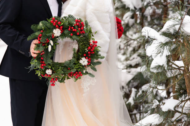 mariage d'hiver. mariée et marié retenant la couronne de noel - christmas wedding bride winter photos et images de collection