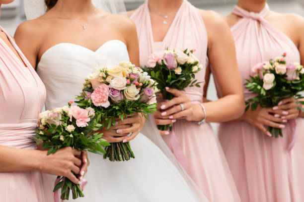 sposa e damigelle in abiti rosa in posa con mazzi di fiori il giorno del matrimonio. buon concetto di matrimonio e festa di matrimonio - abito da sposa foto e immagini stock