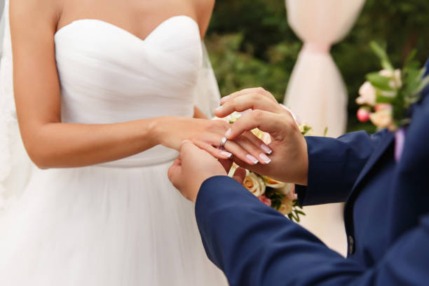 boda, concepto de matrimonio. el novio pone el anillo de boda en la novia"u2019s dedo en la ceremonia de la boda - young women wedding married engagement ring fotografías e imágenes de stock