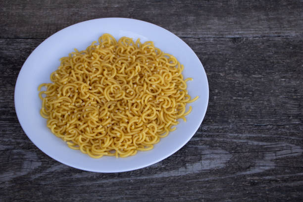 istock Un-cooked pasta in a plate on wooden background 1183720124