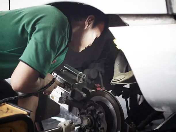Mechanic man repairing brake use grinding machine and vehicle brake-disc. Disc brake system repair.