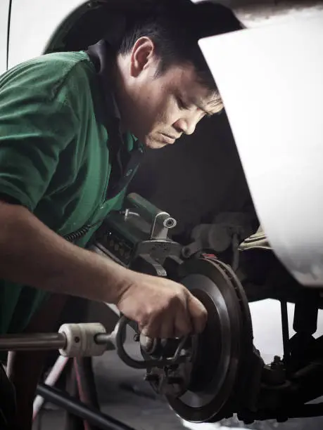 Brake disc grinding machine. Auto mechanic checking the grinding machine - Vehicle brake-disc turning machine.