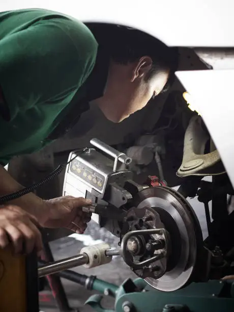 Brake disc grinding machine. Auto mechanic checking the grinding machine - Vehicle brake-disc turning machine.