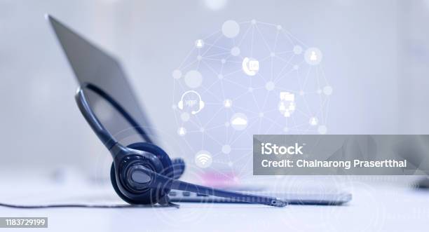 Close Up Headset Of Call Center And Voip Communication With Futuristic Virtual Icon Telecommunication Technology On Office Table In Monitoring Room For Network Operation Job Concept Stock Photo - Download Image Now