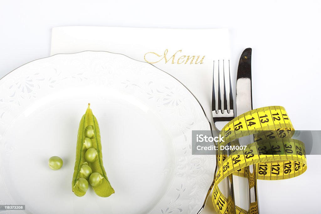 Extreme dieting Pea and measure tape on a plate over white background Color Image Stock Photo