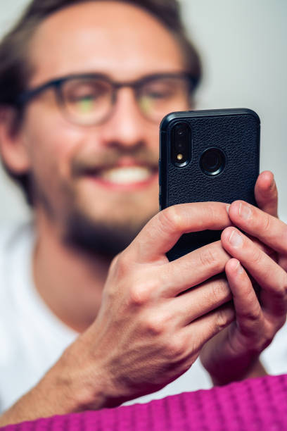 istock Young man in glasses with phone in bed. 1183732102