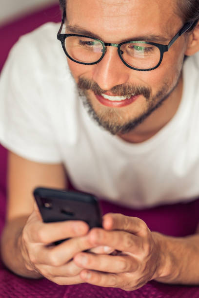 istock Young man in glasses with phone in bed. 1183732888