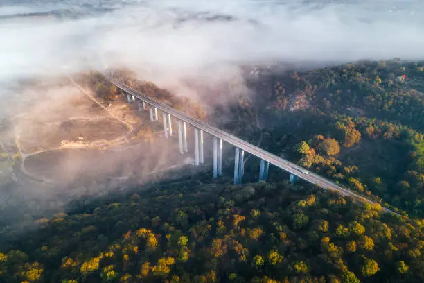 Photo of Mistyc Aerial view of a highway on a viaduct, high tech engeneering construction, ochre colored landscape and low clouds in the sky.