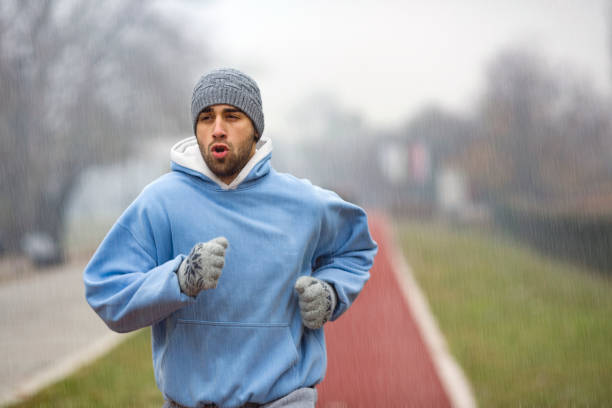 No matter the weather Young man exercising on cold winter day, running. About 25 years old, Caucasian male in warm clothing. all weather running track stock pictures, royalty-free photos & images