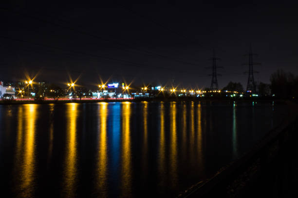 Moscow / Russia-October, 26, 2019: night city with black sky and lanterns with bright reflection in the dark water of the pond