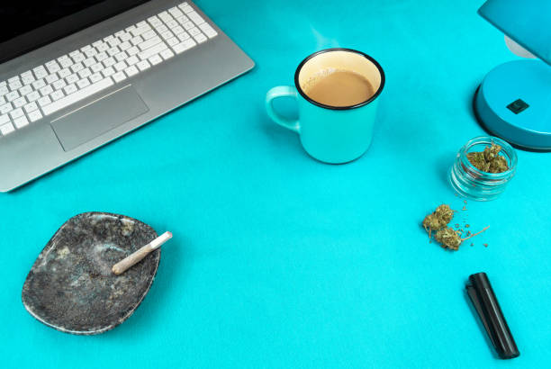 istock Blue work space with marijuana joint, coffee cup, computer and cannabis. Concept of cannabis and work or technology with copy space center. 1183748434