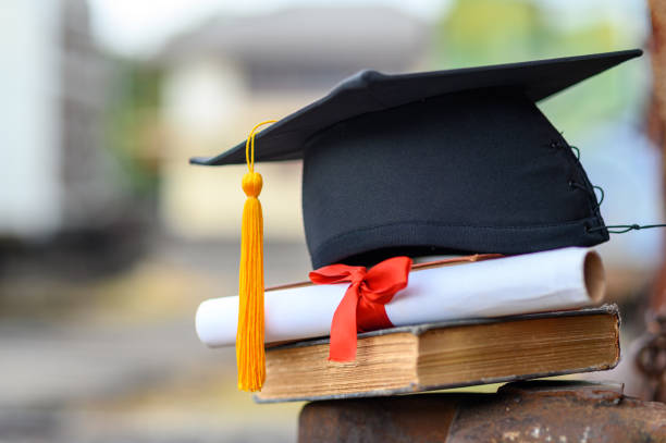 istock Black graduates hat and yellow tassel place an old book 1183749303