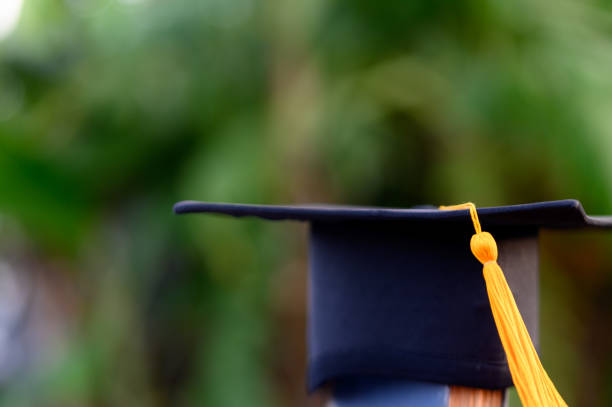 istock Black graduates hat and yellow tassel place an old book 1183749335