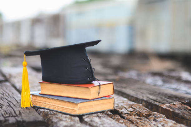 istock Black graduates hat and yellow tassel place an old book 1183749364