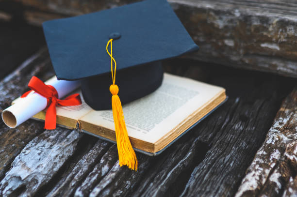 istock Black graduates hat and yellow tassel place an old book 1183749373
