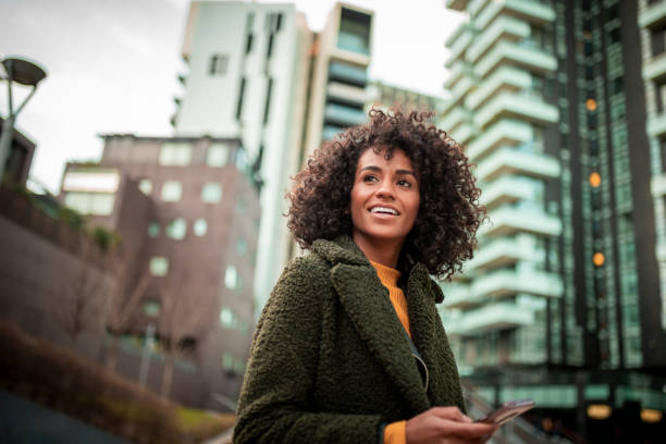 улыбающаяся молодая женщина в центре города - happiness african ethnicity cheerful businesswoman стоковые фото и изображения