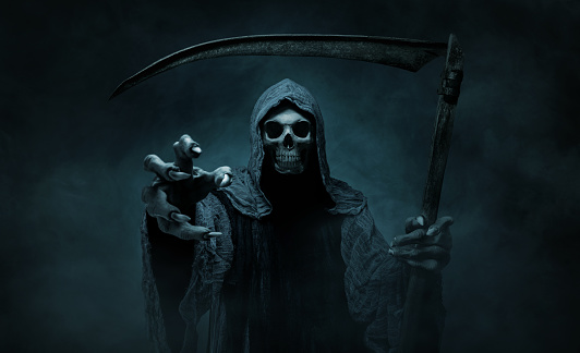 Grim reaper reaching towards the camera over dark misty background with copy space