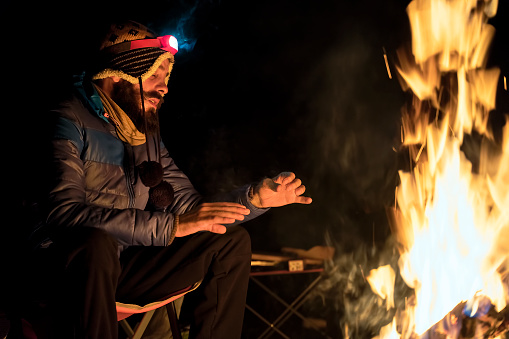 Man warming up with campfire in woods