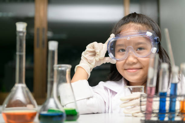 istock Cute little girl wearing safty goggle and lab coat making experiment 1183753664