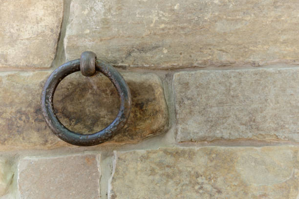 old rusty ring fixed in a stone brick wall old rusty ring fixed in stone brick wall, fastening cattle livestock concept, horizontal stock photo image background with copy space for text medieval restraints stock pictures, royalty-free photos & images
