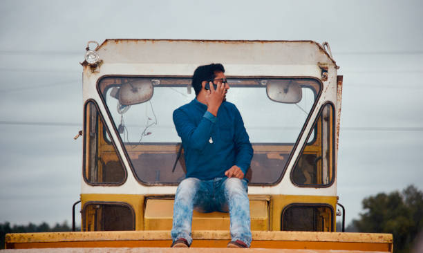 istock Man talking over a cellphone sitting on a yellowish vehicle 1183757878