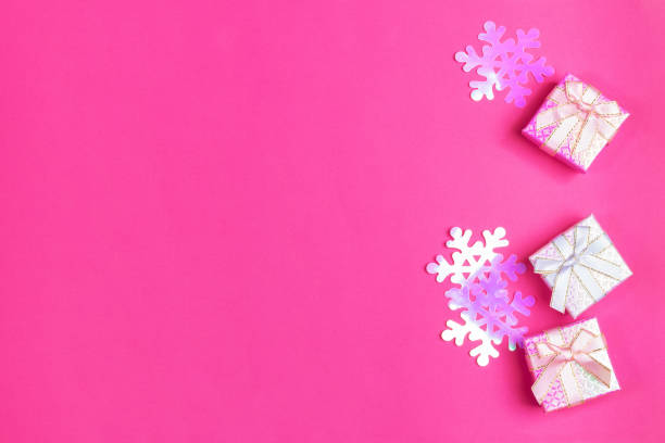 istock Three shiny gift boxes with bows and iridescent plastic purple snowflakes on bright pink background. Christmas festive presents. Top view, copy space. 1183761948