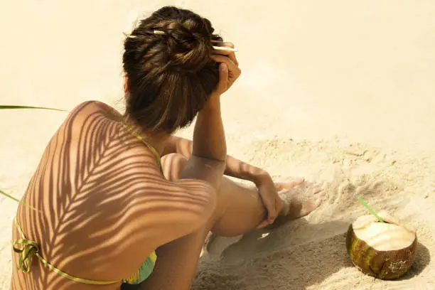 Photo of Woman with coconut drink under palm leaf