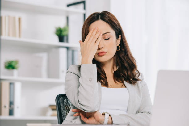 istock exhausted secretary suffering from headache while sitting with closed eyes and holding hand near head 1183763376