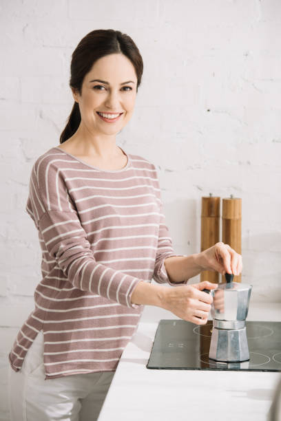istock young, cheerful woman looking at camera while preparing coffee in geyser coffee maker 1183763394