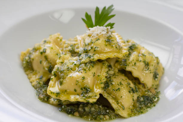 Italian ravioli stuffed with ricotta cheese and pesto Italian raviolis stuffed with ricotta cheese, spinach and served with pesto sauce and grated parmesan cheese. ricotta photos stock pictures, royalty-free photos & images